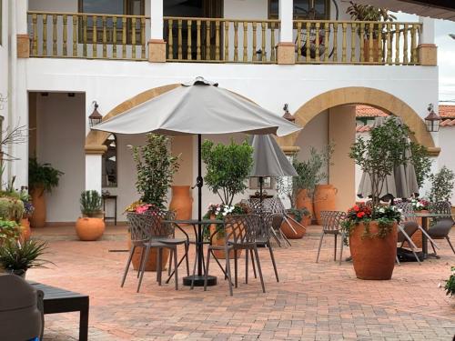 莱瓦镇Santa Lucía Casa Hotel的一个带桌椅和遮阳伞的户外庭院
