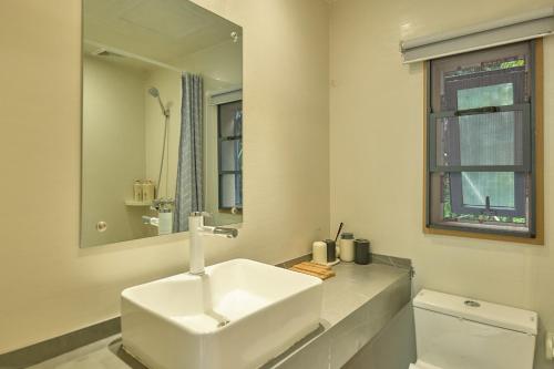 张家界驻马溪休闲度假山庄的白色的浴室设有水槽和镜子