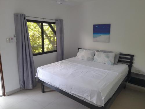 道伊斯Bohol Jewel Resort的一间卧室配有一张带白色床单的床和一扇窗户。