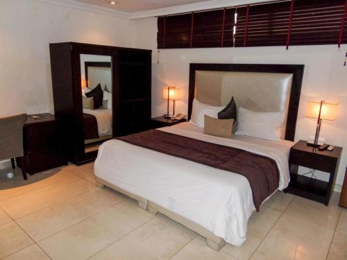 拉各斯S & S Hotel & Suites的一间卧室设有一张大床和一个大镜子