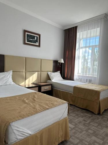 阿克托比Tanzharyk Hotel的酒店客房设有两张床和窗户。