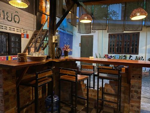 琅勃拉邦Khonesavane Hostel的一间酒吧,房间内设有木桌和椅子