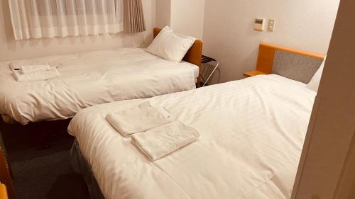 索拉哈Hotel Nepal Inn Sauraha的配有白色床单的酒店客房内的两张床