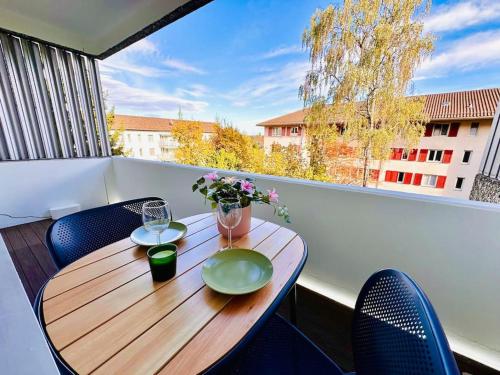 苏黎世Modern City Studio with Balcony的阳台上的木桌,配有两杯玻璃和鲜花