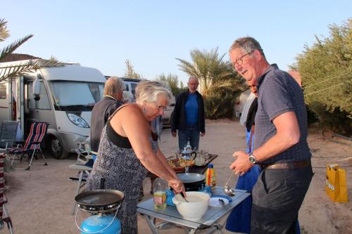 TattaCamping , Maison d'hôte Bivouac hyatt-tata的正在餐桌上准备食物的男人和女人