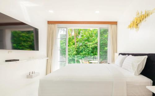 卡塔海滩Rudi Condo by Q Conzept的卧室配有白色的床和窗户。