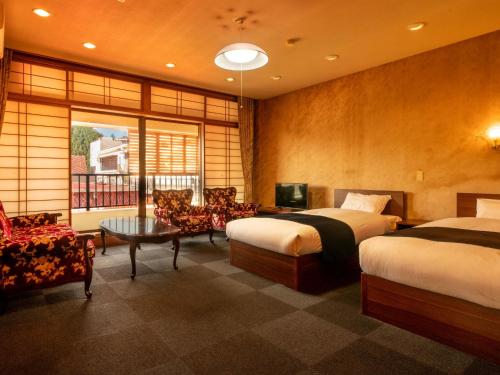 ObamaYukai Resort Unzen Toyokan的酒店客房设有两张床和一张桌子。