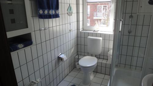 乌埃克尔明德FEWO-bis-2-Pers-inmitten-den-Yachthafens-Ueckermuende-Stettiner-Haff-Ostsee的白色瓷砖浴室设有卫生间和窗户。