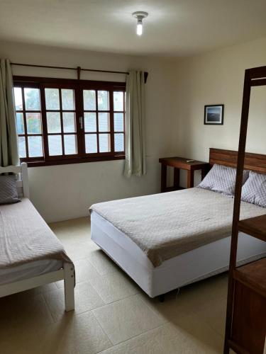 伊比拉奎拉Townhouse composta por 4 triplex duas suítes a duas quadras do mar的一间卧室设有两张床和窗户。