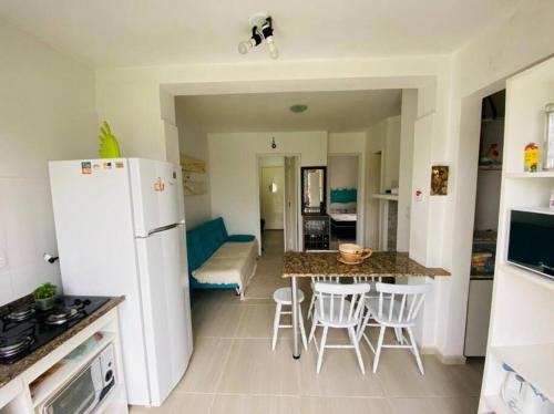 卡庞达卡诺阿Apartamento em Capão Novo com piscina的厨房配有白色冰箱、桌子和椅子