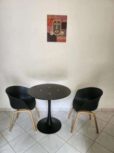 马罗尼河畔圣洛朗Résidence DENGUELE Studio的一张桌子和两把椅子坐在墙上