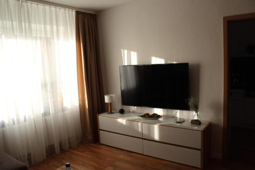 Geyerhaustierfreundliche Ferienwohnung Greifenbach的客厅配有梳妆台上的平面电视
