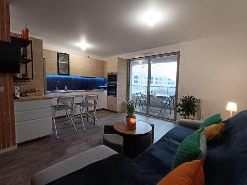 波尔多Chambre dans un joli appartement cosy的一间带蓝色沙发的客厅和一间厨房