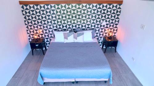 南圣胡安Tropical Loft Home - Ocean View的一间卧室配有一张床和两张带台灯的桌子。