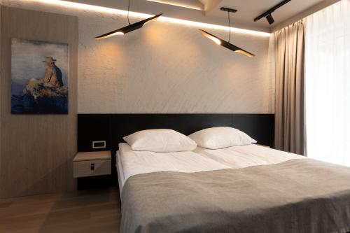 库瑞尼卡慕斯卡四风度假屋的卧室配有一张床,墙上挂有绘画作品