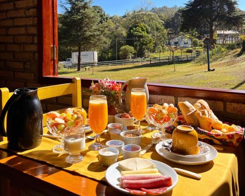 蒙特韦尔迪Chalés Recanto da cachoeira的餐桌,带食物和橙汁杯