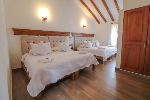 莱瓦镇Hotel las Palmas的一间卧室配有两张带白色床单和木地板的床。