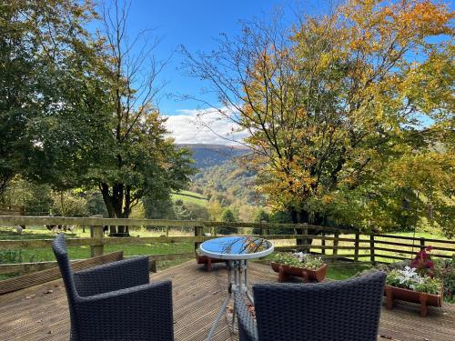 海伯敦桥Weather Hill Cottage, Hebden Bridge的木制甲板上配有两把椅子和一张桌子的庭院