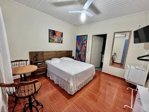 伊利亚贝拉Recanto Toca das Plantas de Ilhabela I的一间卧室配有一张床、一张桌子和吊扇