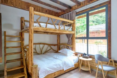 张家界驻马溪休闲度假山庄的一间卧室设有双层床和梯子