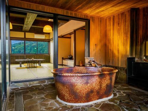 真庭市Yukai Resort Terunoyu的一个带桌子的房间,有一个大型铜制浴缸
