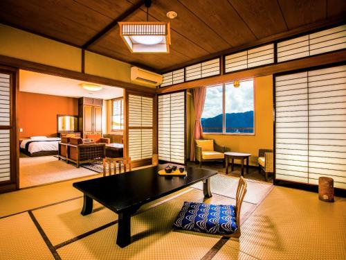 下吕市Yukai Resort Gero Saichoraku Bekkan的一间带桌子的客厅和一间卧室