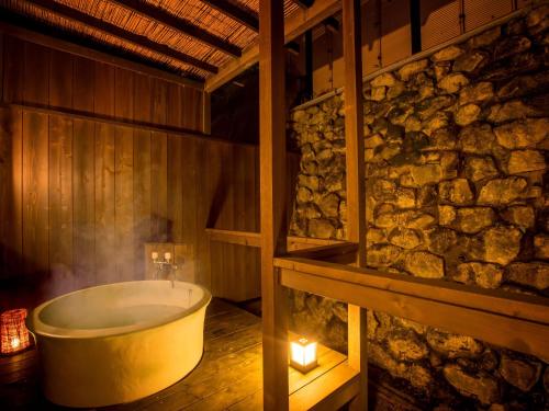 下吕市Yukai Resort Gero Saichoraku Bekkan的石墙客房内的浴缸