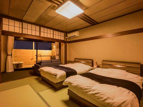 加贺Yukai Resort Premium NEW MARUYA Hotel的一间卧室设有两张床和窗户。
