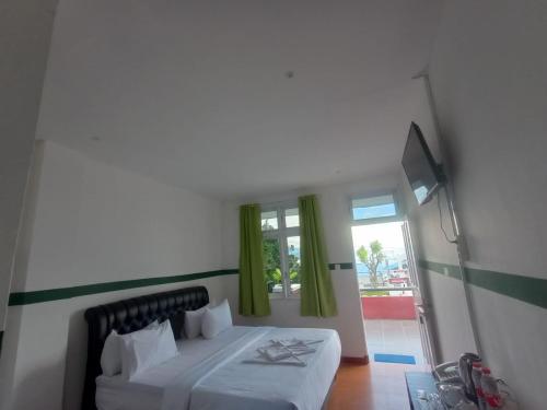 巴利盖Hotel Ompu Herti的一间卧室设有床铺和一个带绿色窗帘的窗户。