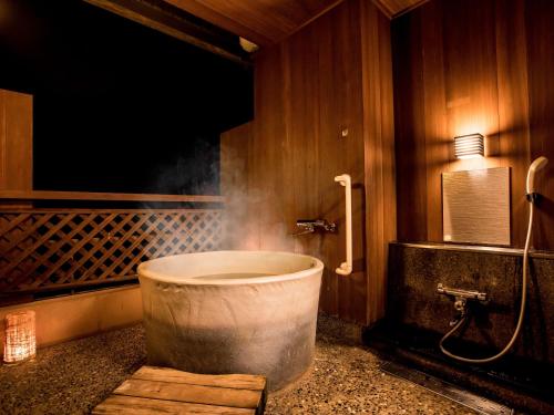 加贺Yukai Resort Premium Yoshinoya Irokuen的带浴缸的浴室,其中有烟雾