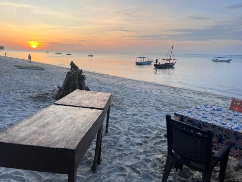 基林多尼Maweni CoralBay Beach Villa的海滩上的桌椅,日落