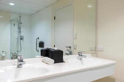 陶朗加阿米蒂奇酒店及会议中心的一间带两个盥洗盆和大镜子的浴室