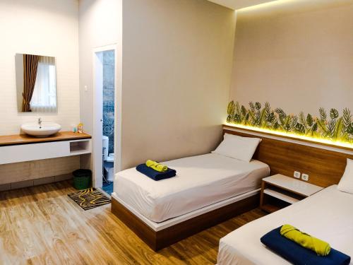GondowulungCaniga Hotel Yogyakarta的酒店客房设有两张床和盥洗盆