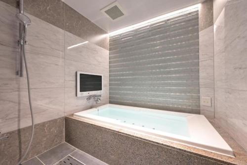 名古屋Hotel Pasadena レジャーホテル的带浴缸、电视和淋浴的浴室。