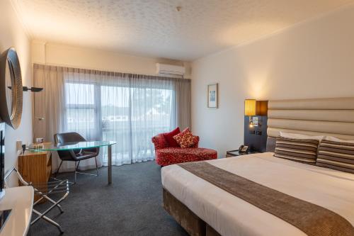 陶朗加阿米蒂奇酒店及会议中心的配有一张床、一张书桌和一扇窗户的酒店客房