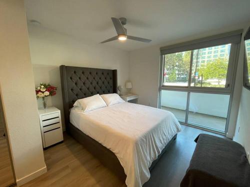 尔湾Luxurious Apartment Bardeen New Port Beach 1 Bedroom的一间卧室配有一张带吊扇和窗户的床。