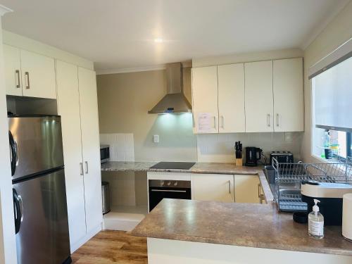 金斯科特Kangaroo Island Homestays的厨房配有白色橱柜和不锈钢冰箱