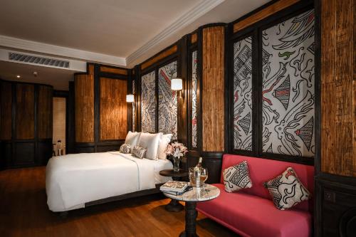 雅加达The Orient Jakarta, a Royal Hideaway Hotel的卧室配有白色的床和红色沙发