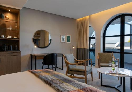 斯泰伦博斯The Hazendal Hotel by NEWMARK的酒店客房带一张床、一张桌子和椅子
