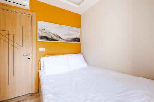 安塔利亚Flat w Balcony 5 min to Beach in Kemer的卧室配有白色的床和黄色的墙壁