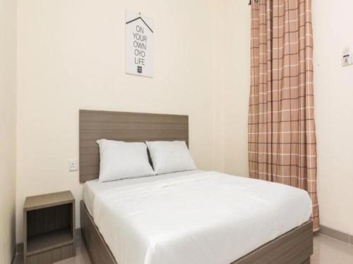 TanjungriauOYO Life 2735 Graha Nirwana的一间卧室配有一张带白色床罩的大床