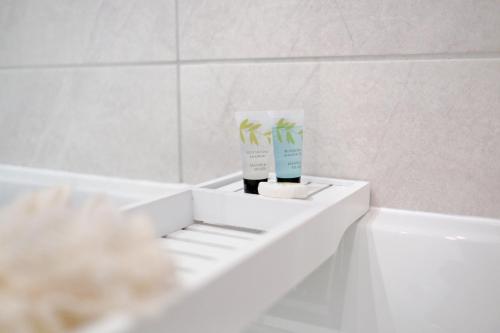 阿伯丁Orange Apartments Belgrave Mansions的浴室设有白色浴缸、一瓶牙膏和容器