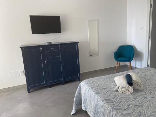 诺利L'angolo di Anna的一间卧室配有一张床、一台电视和一张蓝色椅子