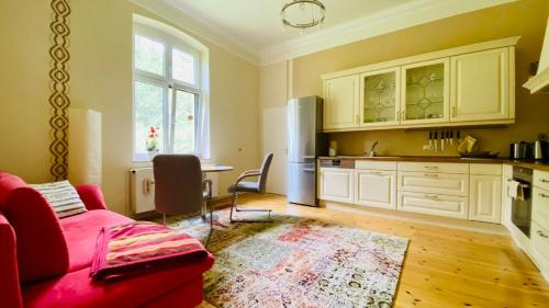 费尔德伯格Ferienwohnung Villa am Haussee的一间带红色沙发的客厅和一间厨房