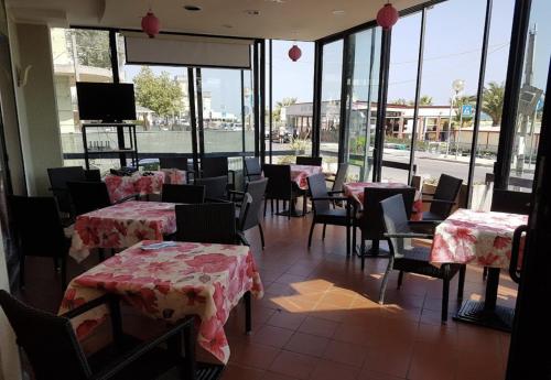 里米尼Hotel Bonaria的用餐室设有桌椅和窗户。