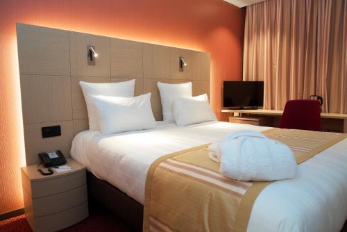 日内瓦纳什机场酒店的一间酒店客房,配有一张带毛巾的床