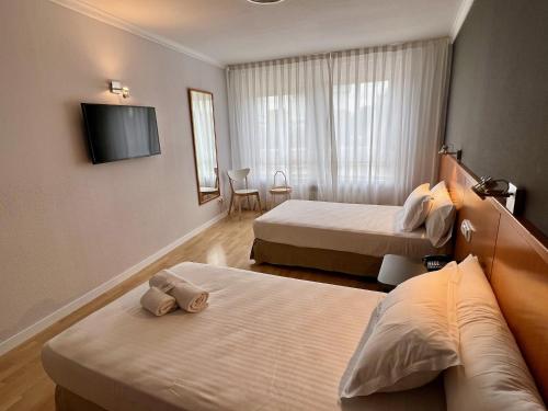 马德里AP Hotel Madrid Airport的酒店客房设有两张床和一台平面电视。