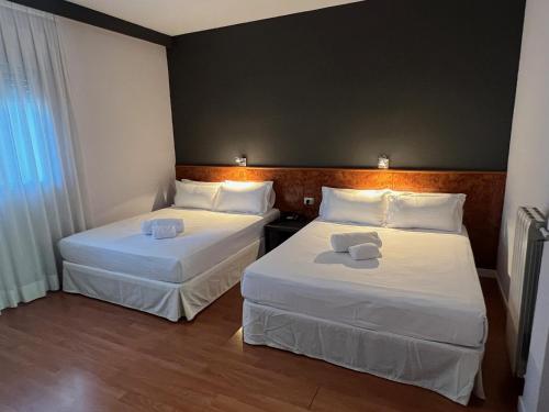 马德里AP Hotel Madrid Airport的配有白色床单的酒店客房内的两张床