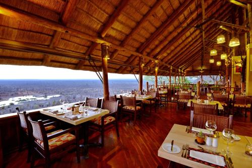 维多利亚瀑布维多利亚瀑布野生酒店的一间设有桌椅的餐厅,享有美景。