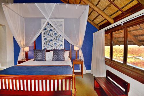 维多利亚瀑布维多利亚瀑布野生酒店的一间卧室配有一张蓝色墙壁的床和一扇窗户